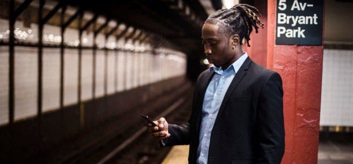 Man holding his cellphone while standing at train station