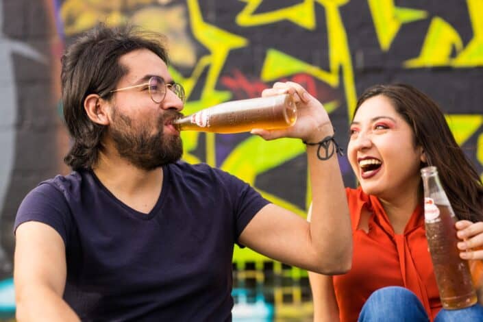 Man and woman laughing while drinking soda together.