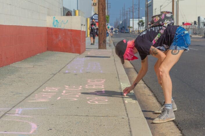woman writing with chalk on sidewalk
