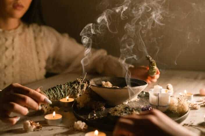 woman burning herbs with candles