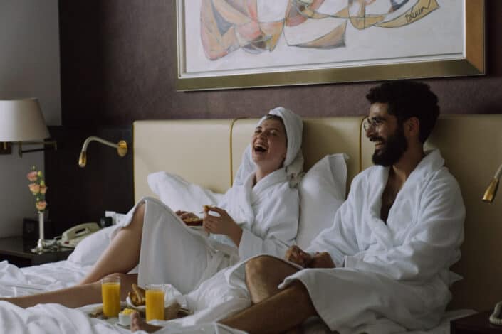 couple wearing robes having breakfast in bed