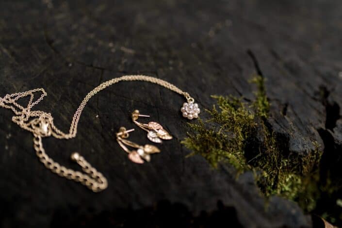 gold necklace and earrings next to green moss