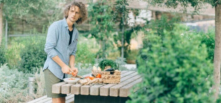 man cutting tomatoes in an outdoor setting