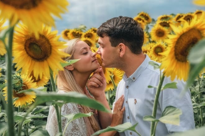 man and woman kissing on sunflower field - cute date ideas