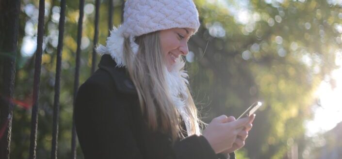 Girl reading text from her phone outdoors.