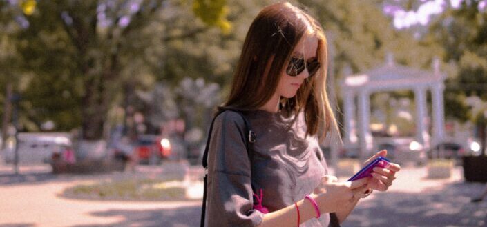 Girl walking and looking down to read a text.