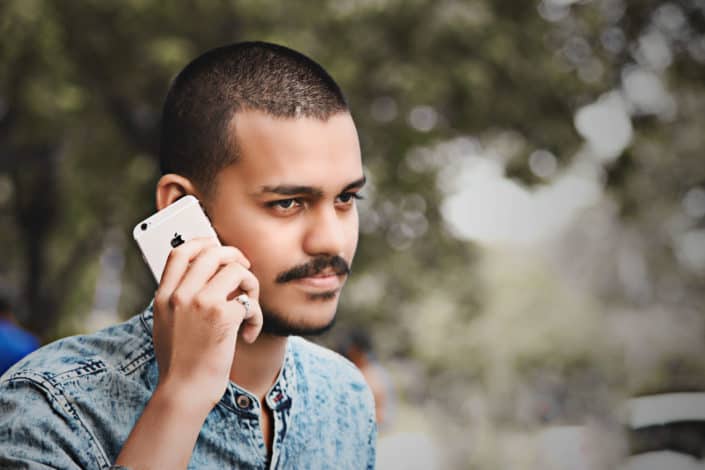 man holding his cellphone through his ears