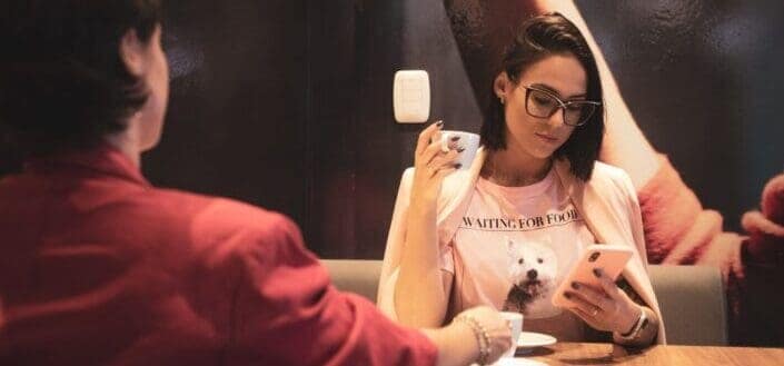 Couple sitting in a cafe with girl looking at her phone.