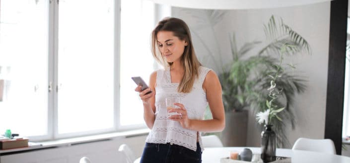 girl drinking water while texting