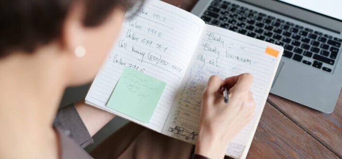 Woman scribbling notes on an open notebook