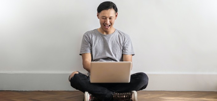 man in casual clothes laughing while watching 