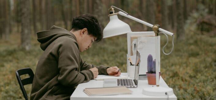 A man working on a desk in the middle of the forest