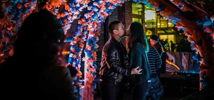 man and woman kissing under a flower gazebo