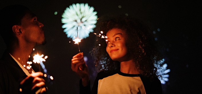 man and woman smiling while holding sparkles during a fireworks display