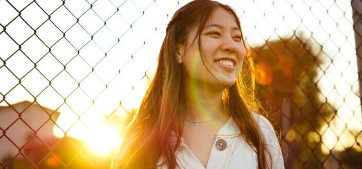 Woman by the fence, smiling.