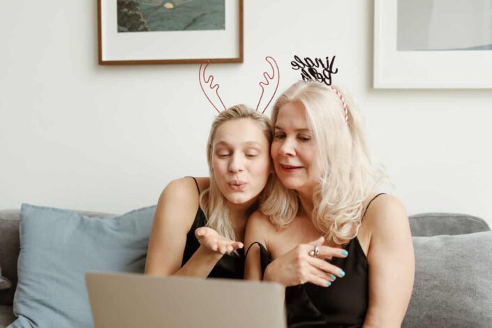 two women striking a pose in front of a laptop