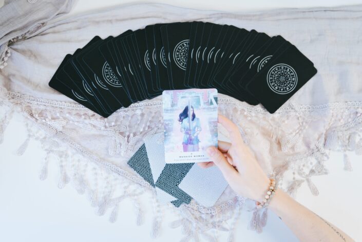tarot cards laid on a table with a hand holding one up