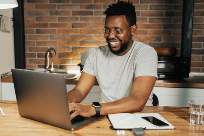 Guy smiling while working on his laptop