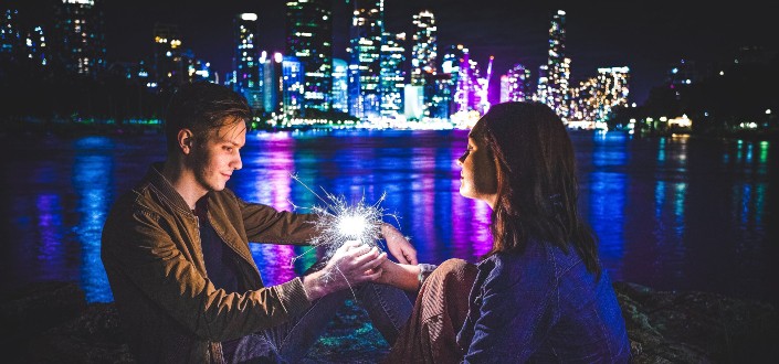 man and woman holding sparkler near river