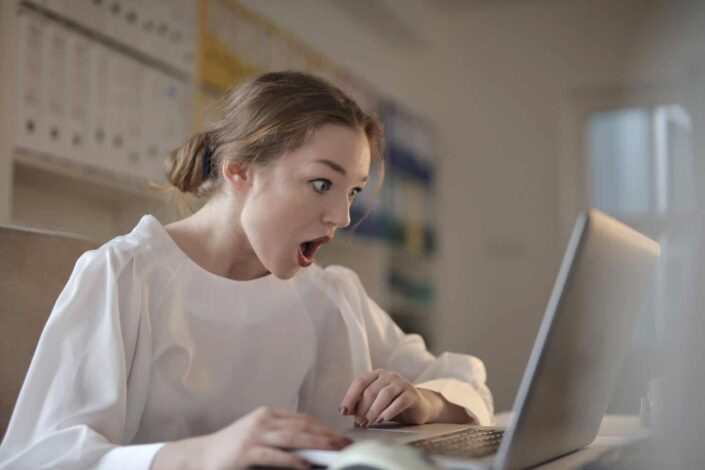 woman having a shocked facial expression in front of her laptop 