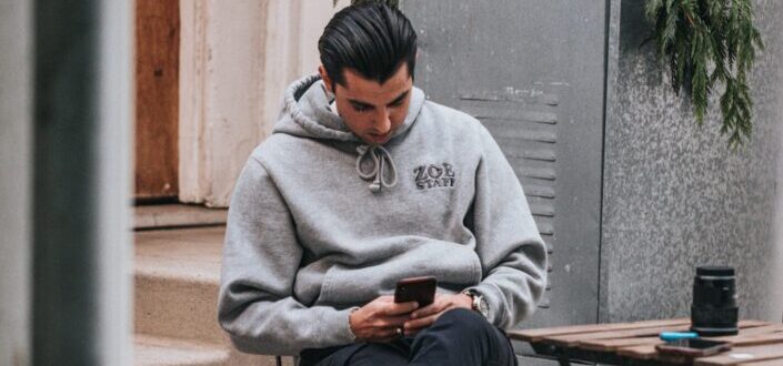 Man in gray hoodie busy on his phone