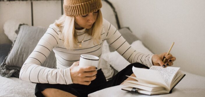 woman holding a cup while looking through her notebook