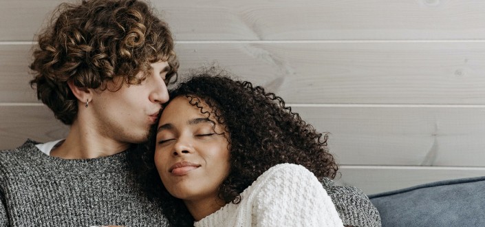 curly man kissing a curly woman's forehead