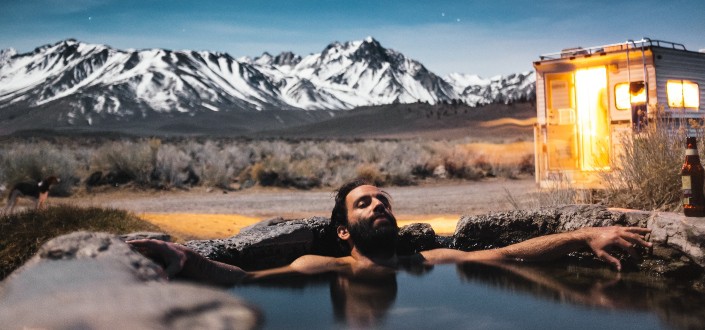 man taking a bath under bright stars and mountains in the background