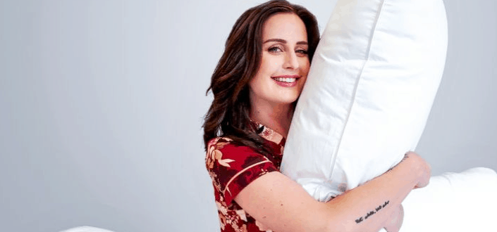 smiling woman hugging a white pillow