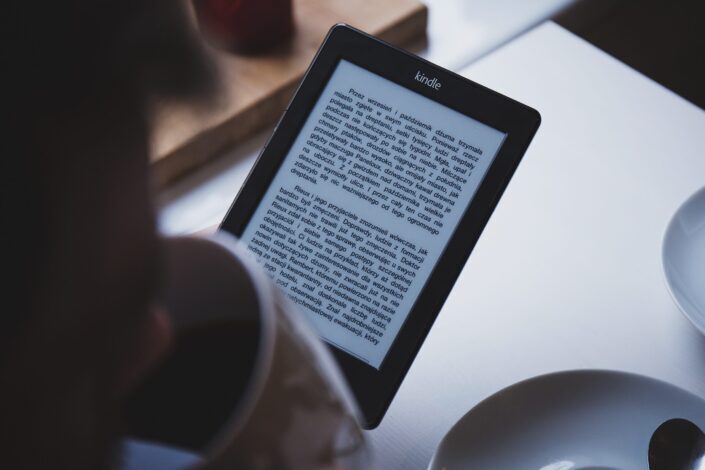 silhouette of a man drinking coffee while looking at his tablet