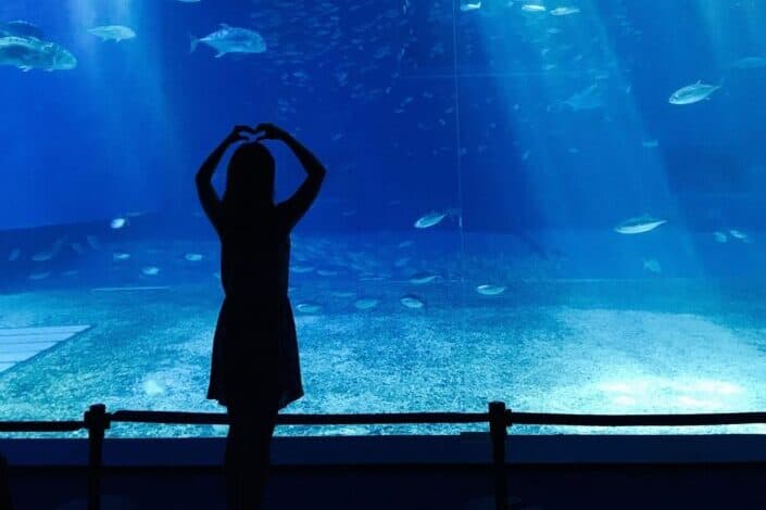 a woman with a heart sign outside an aquarium