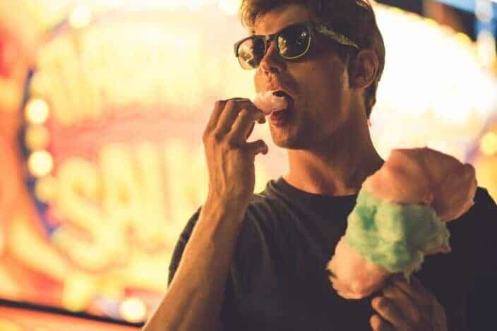 Man wearing sunglasses eating cotton candy