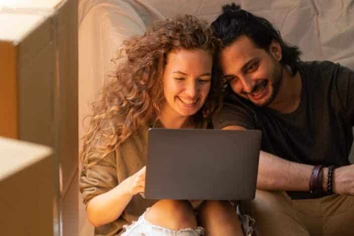 Couple cheerfully watching something on a laptop.