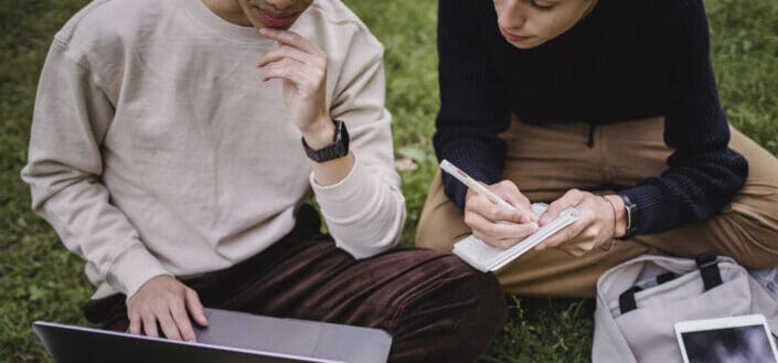 man and woman using laptop while studying in park