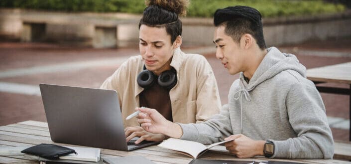 Two guys researching together and taking notes.