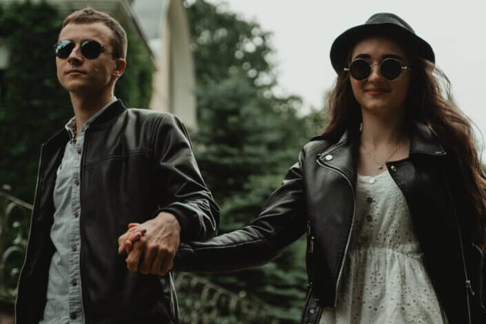 Couple on sunglasses, holding hands while walking.