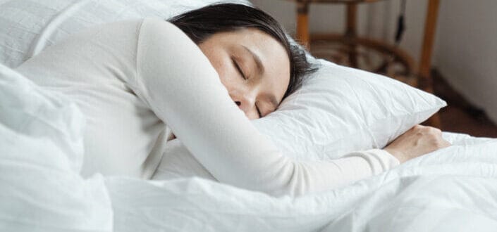 woman in white sleeping on white bed