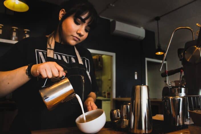 a barista pouring milk in a cup