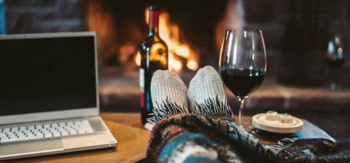 laptop beside wine glass on brown wooden table