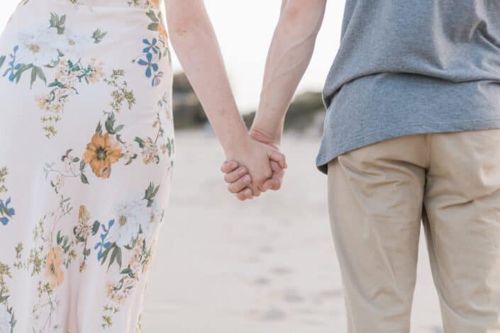 couple holding hands on sand field