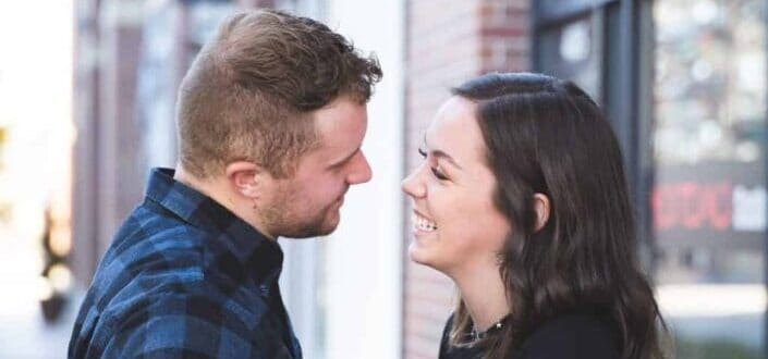 man in blue and white plaid dress shirt kissing woman in black blazer