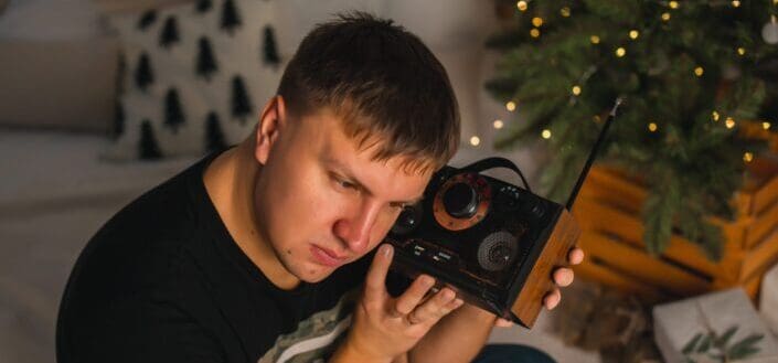 Man listening to radio by a Christmas tree