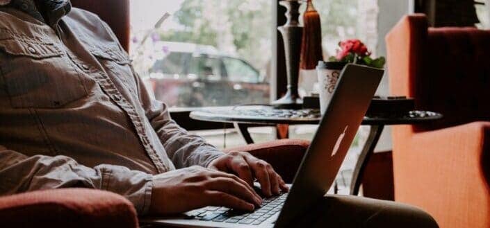 man sitting while using MacBook on lap