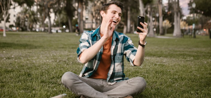 man smiling while waving his hand in front of his phone