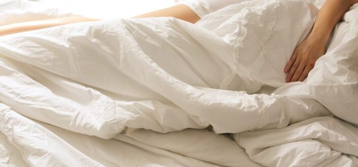 person lying on bed covered with white blanket