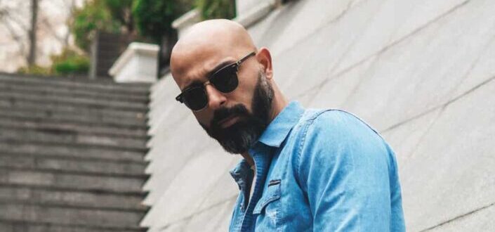 A bearded hairless man in sunglasses