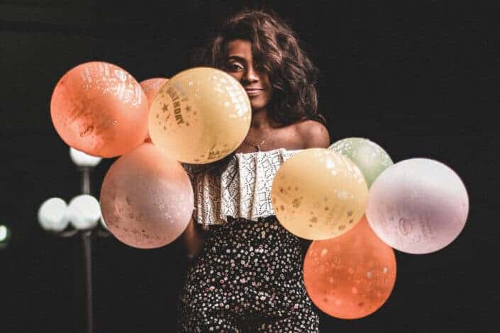 a woman holding varying colors of balloons