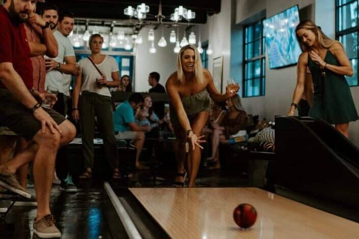 group of people watching woman playing bowling