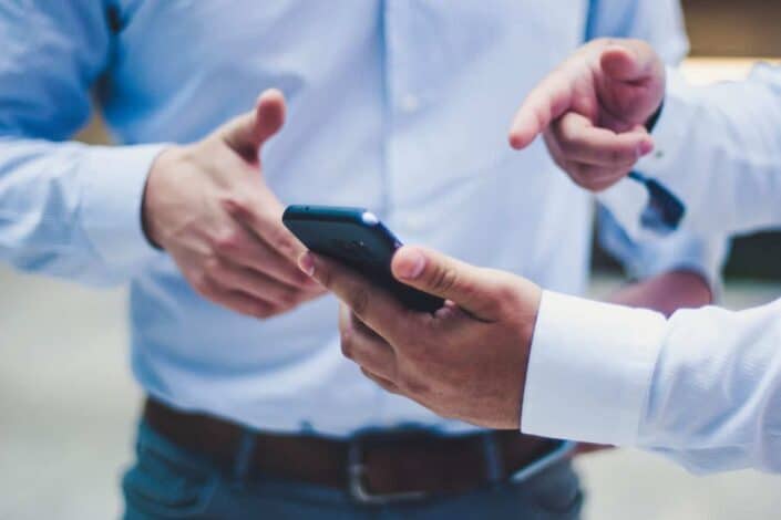 two men pointing at a phone
