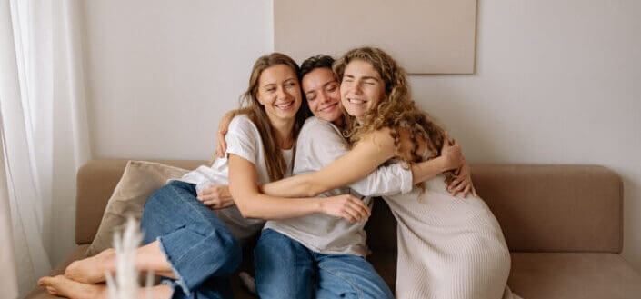 three women hugging on a couch